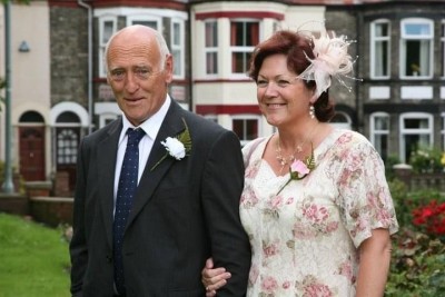 Mr and Mrs Woodgate looking smart in their wedding attire standing outside some houses.